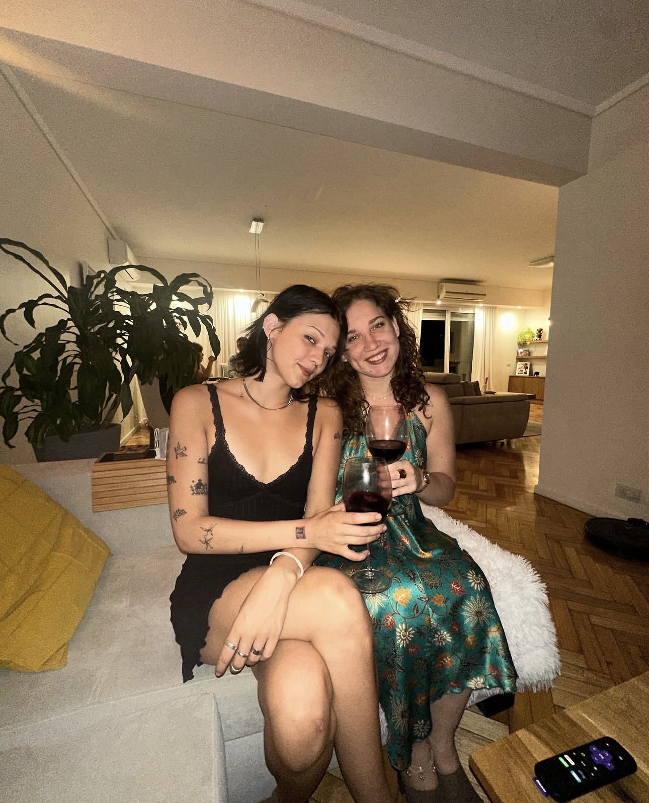 Two friends relaxing with wine on a sofa at home