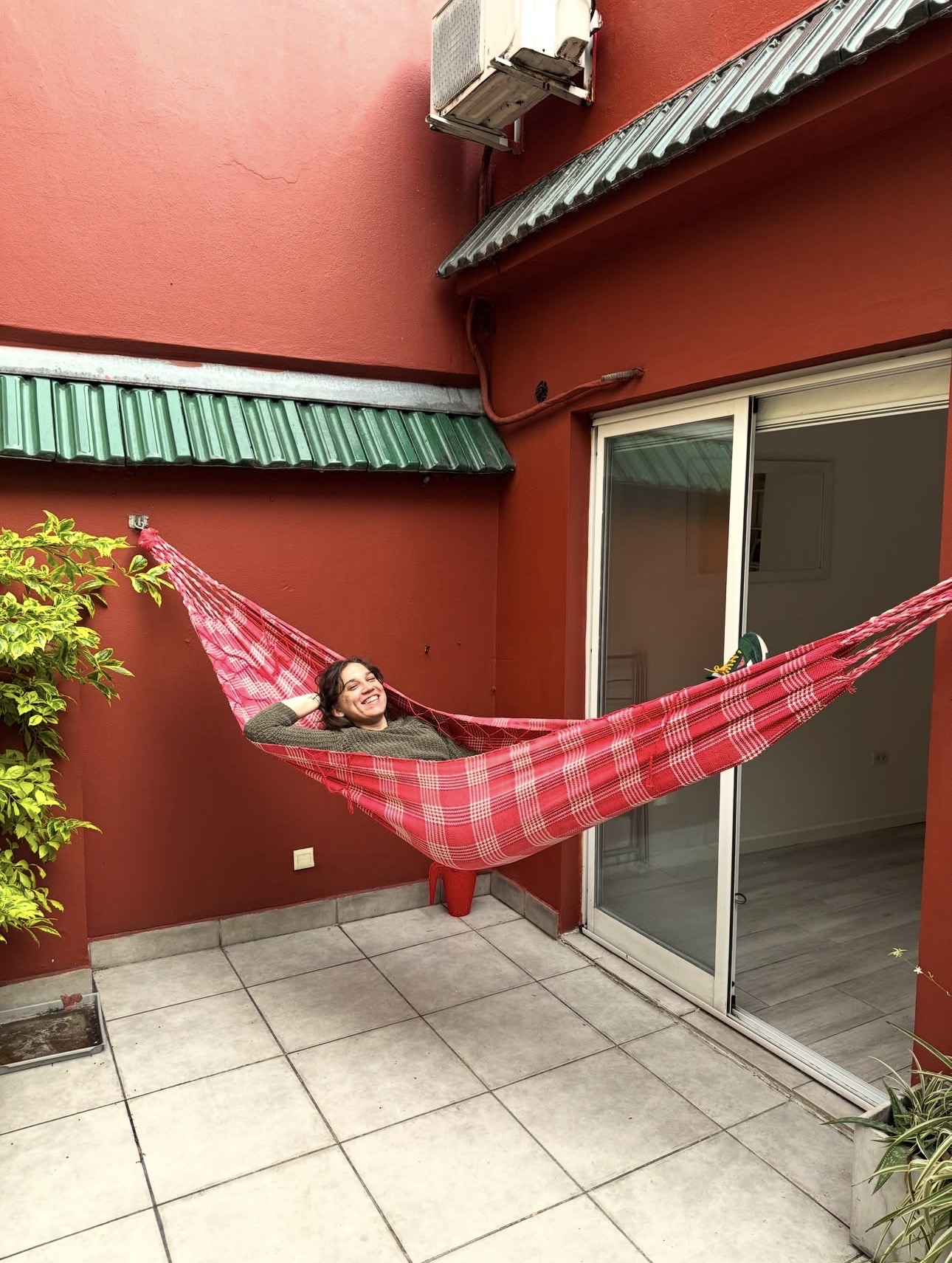 Mica relaxing in a red hammock in a courtyard