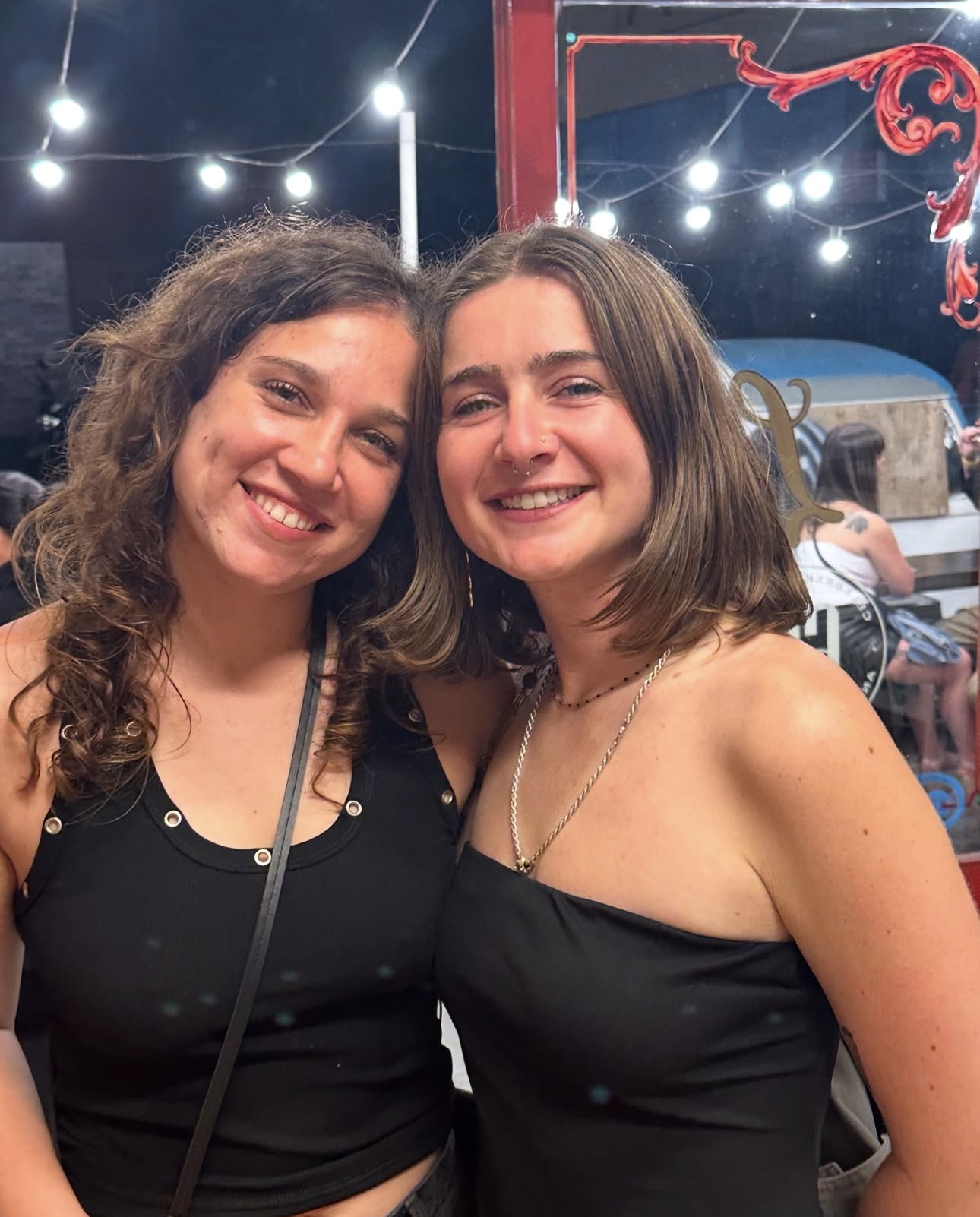 Two friends smiling at a nighttime street fair in Buenos Aires
